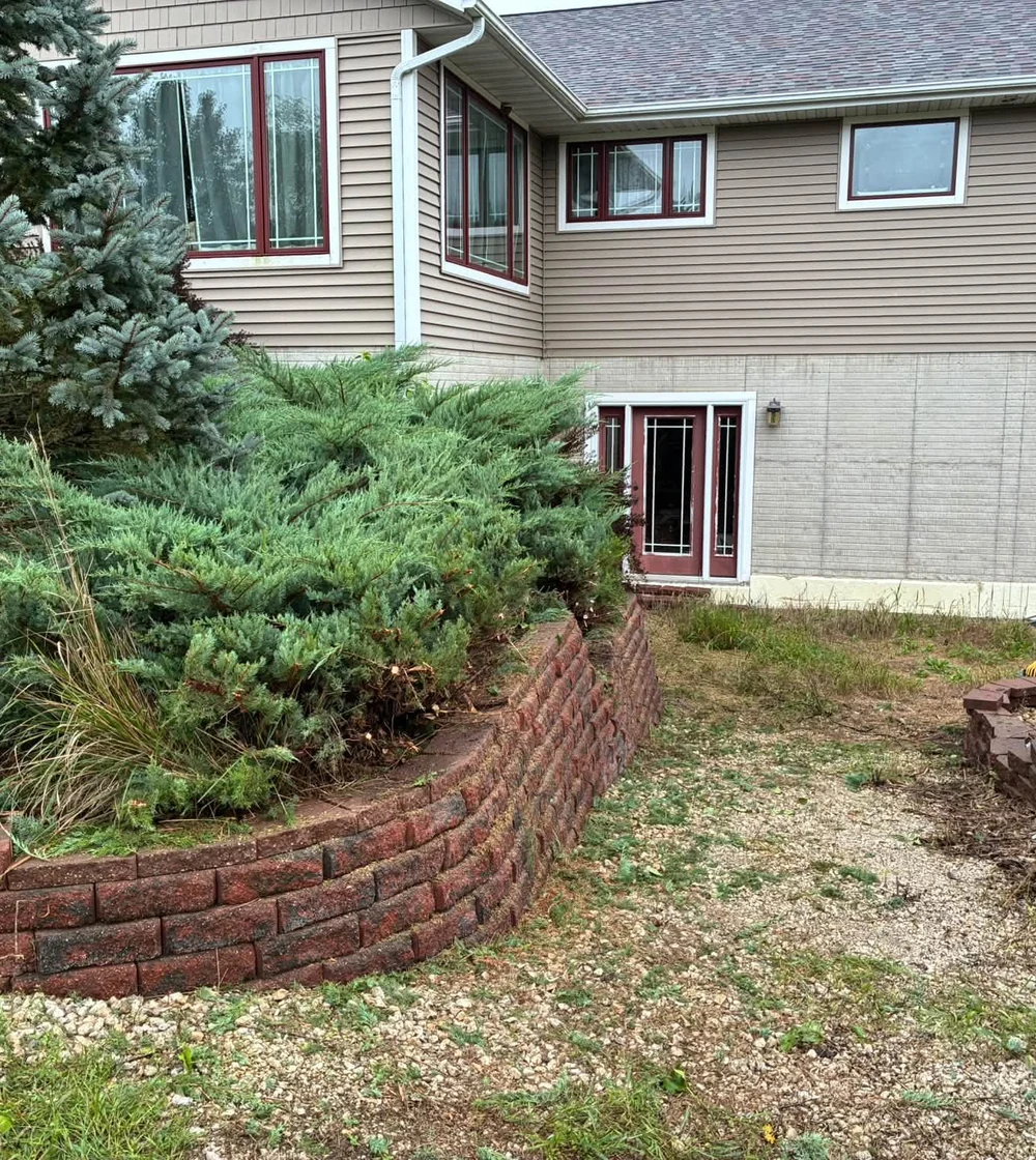 A restored red block wall and trimmed hedge at a residential property.