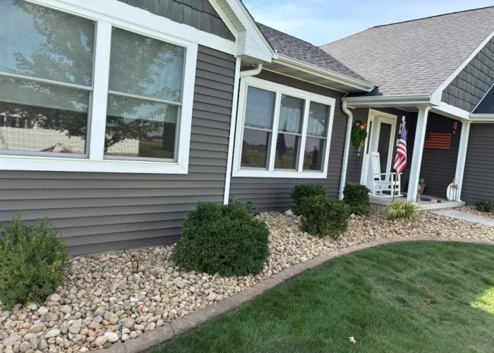 River-rock bed refresh along the front of a gray Kewanee home.